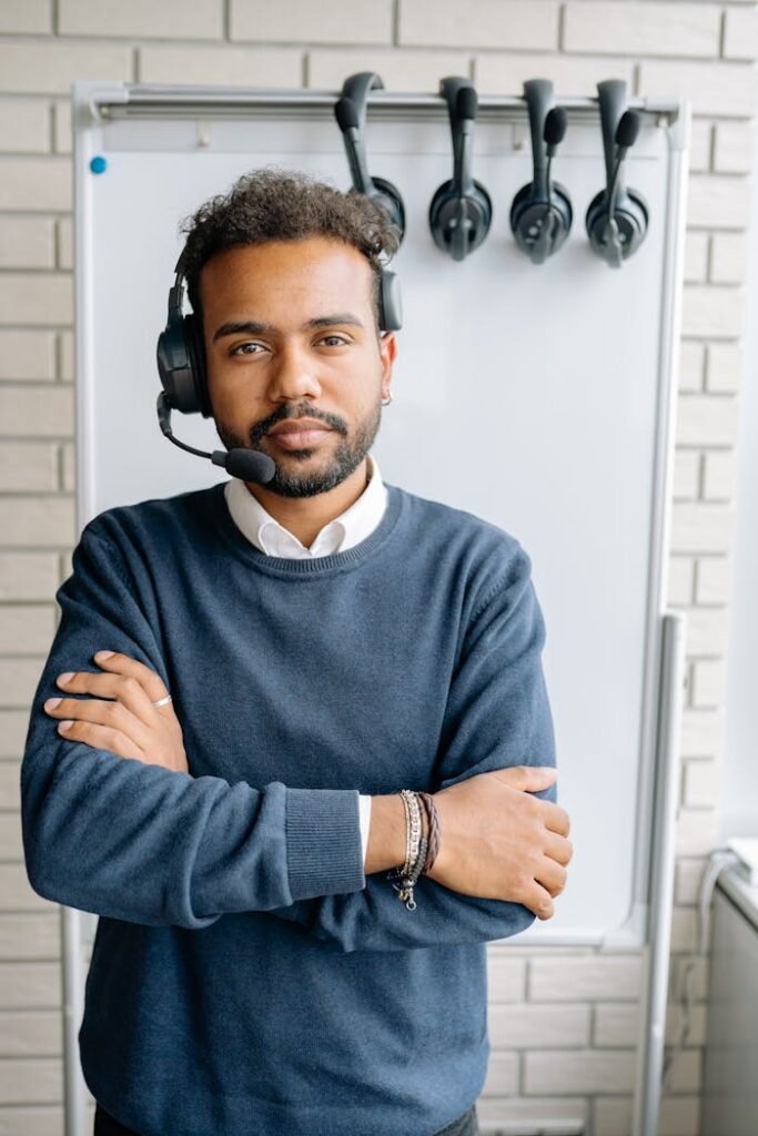 Serious call center agent with crossed arms, wearing a headset, standing by a whiteboard.